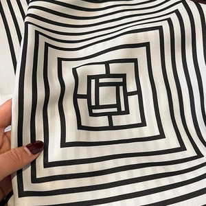 Detailed view of striped silk scarf texture and geometric pattern in black and white