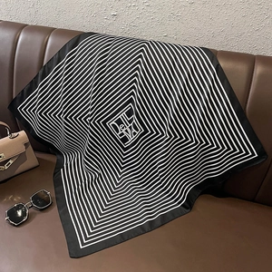 Fashionable black and white striped silk scarf displayed on a luxury leather surface