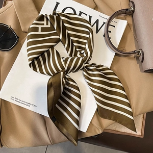 Olive green and cream striped satin silk scarf styled on a beige blazer and grey handbag