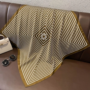 Detailed view of a striped silk scarf in brown and gold draped on a leather background