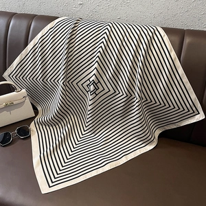 Detail of striped silk square scarf with geometric pattern on a leather background