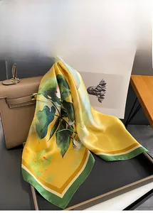 Silk scarf with lotus print tied on a leather bag handle for elegant decoration