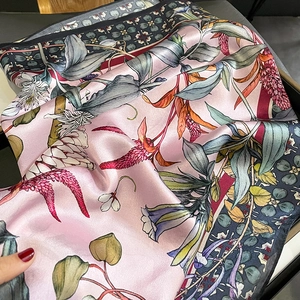 Close-up of soft pink silk scarf with elegant floral prints and satin texture