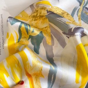 Elegant silk scarf with yellow and grey abstract floral print on soft folded fabric
