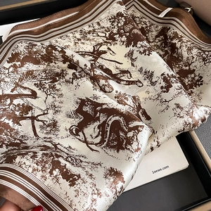 Detailed close-up of brown Toile de Jouy silk scarf with nature prints in a gift box