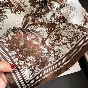 Detail of silk scarf showing Toile de Jouy pattern and smooth satin texture in brown