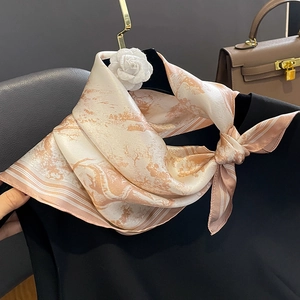 Elegant silk scarf with abstract pink landscape pattern draped on a hanger