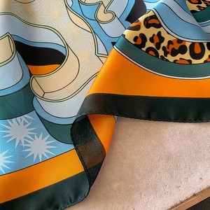 Detailed macro view of the satin leopard print scarf with colorful geometric block patterns
