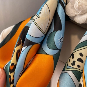 Detailed view of leopard print silk scarf with orange and blue geometric patterns