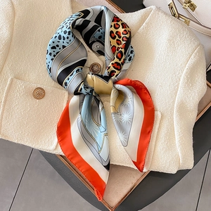 Silk feel leopard print square scarf with geometric patterns on a white wool coat
