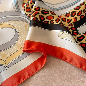 Close-up of leopard print satin scarf with grey geometric lines and orange hem detail