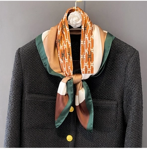 Close-up of a silk scarf with H-pattern and geometric print on a tweed coat