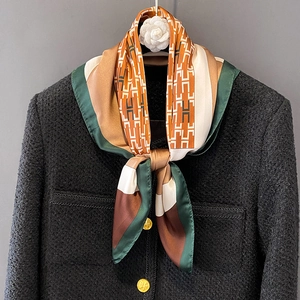 Elegant geometric H-print silk scarf tied on a tweed jacket with camellia decor