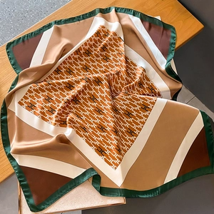 Detailed close-up of glossy satin square scarf with green border and H-pattern design