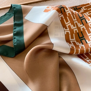 Macro detail of silk scarf with geometric chain pattern and refined rolled edges