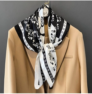 Détail d'un foulard en soie à imprimé camélia drapé sur un blazer de couleur camel