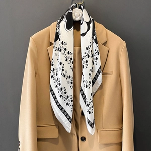 Élégant foulard en soie camélia avec motifs floraux noirs sur un blazer kaki