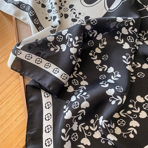 Élégant foulard en soie camélia avec motif floral noir et blanc sur surface en bois