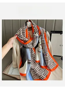 Detail of elegant houndstooth silk scarf with orange borders draped over knitwear