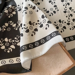 Détail macro d'un foulard en soie à motif camélia noir et blanc avec bordure roulottée