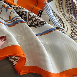 Detail shot of elegant equestrian silk scarf with horse bit and belt patterns in orange