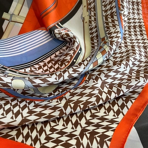 Close-up of silk-textured houndstooth scarf with equestrian buckle and geometric patterns
