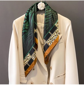 Detail of silk scarf with leopard and tiger print texture on a chic beige blazer