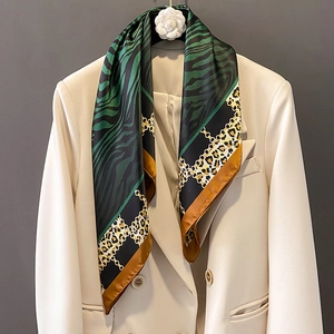 Elegant silk scarf with leopard print and golden chain pattern on beige blazer