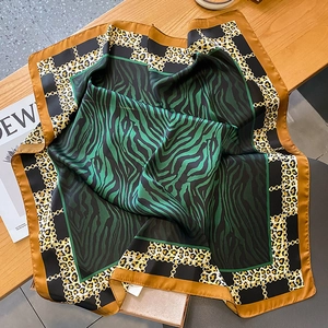 Detail of square silk scarf with green zebra and leopard print with gold chain pattern