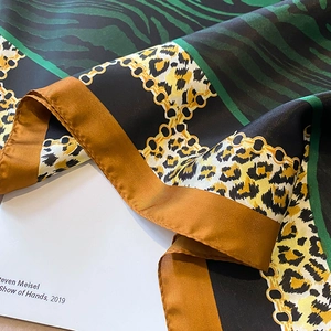 Detailed view of silk leopard print scarf with golden chain pattern and satin luster