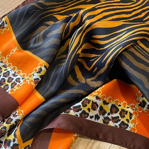 Close-up of leopard and zebra print silk scarf with golden chain details and satin finish