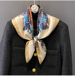 Close-up of elegant floral silk scarf paired with black tweed jacket and camellia brooch