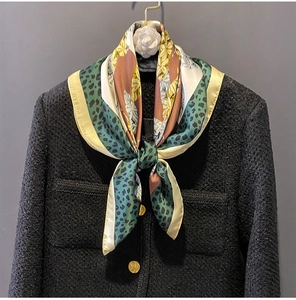Detail of floral leopard silk scarf tied on tweed jacket with camellia brooch
