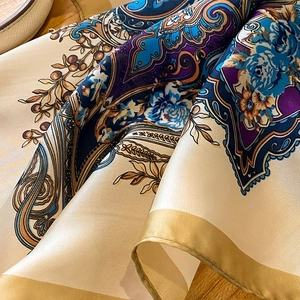 Macro shot of silk scarf with paisley floral pattern and handmade golden rolled edges