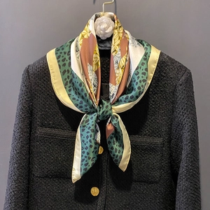 Elegant patterned silk scarf with floral and leopard prints on a black tweed jacket