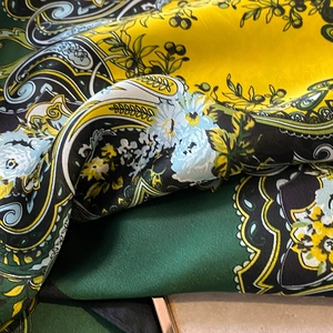 Detailed close-up of smooth silk square scarf with colorful paisley and floral patterns