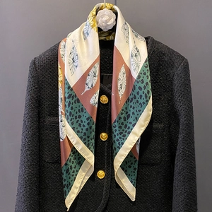 Elegant silk scarf with leopard and leaf prints draped over a tweed coat with camellia