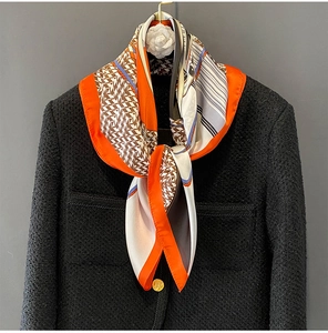 Detail view of houndstooth silk scarf on black tweed jacket with camellia flower