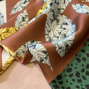 Close-up of silk scarf showing leaf prints and leopard pattern with elegant draping