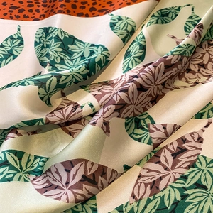 Detailed macro view of soft silk scarf fabric with leopard print and tropical leaf patterns