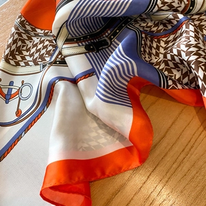 Detail of silk scarf with equestrian horse motifs and houndstooth pattern on wood