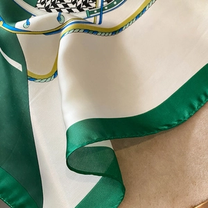 Close-up of silky houndstooth scarf with emerald geometric patterns and rolled edges