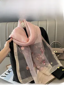 Detailed embroidery of pink plum blossoms on a silk blend scarf with golden silk edges