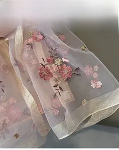 Close-up of floral embroidery on silk blend scarf with delicate gold thread and pink flowers
