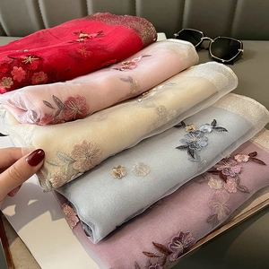 Detail of floral embroidery on lightweight silk blend scarves in vibrant multiple colors