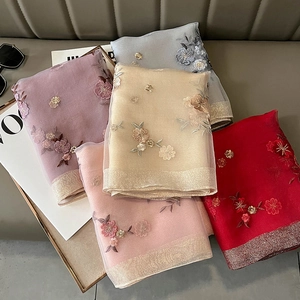 Detail view of silk blend scarves showing five colors with 3D floral embroidery and gold edges