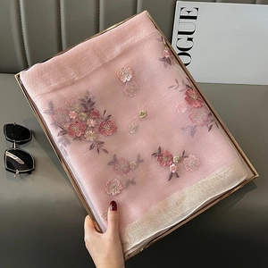 Close-up of pink floral embroidery on silk blend scarf with golden shimmer border