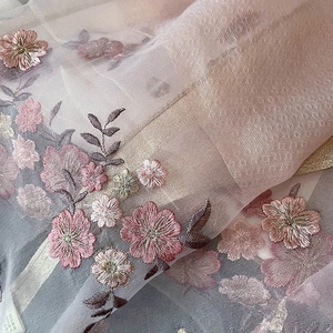Macro shot of detailed floral embroidery on elegant pink silk blend fashion scarf shawl