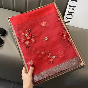 Detailed view of red silk blend shawl with floral embroidery and golden lace edges