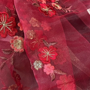 Macro shot of red and gold floral embroidery on silk blend scarf fabric texture